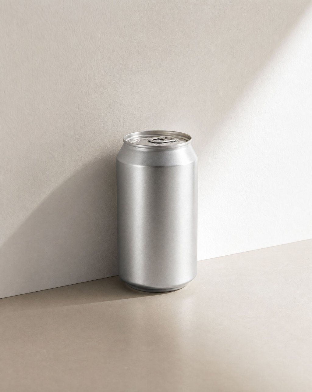 An aluminium can in a pale corner with hard sunlight throwing a crisp diagonal shadow