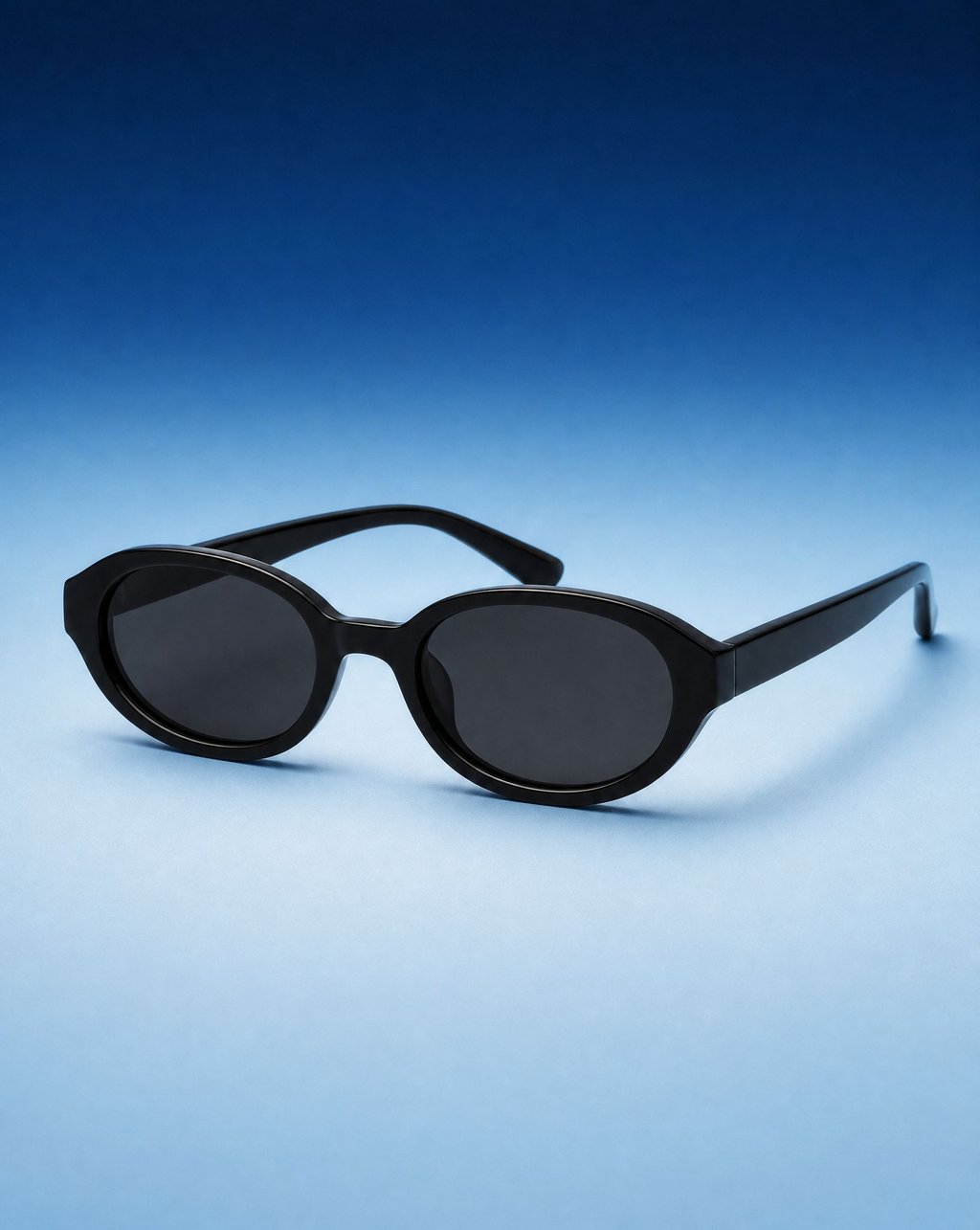 Black oval sunglasses on a blue gradient backdrop under soft even light