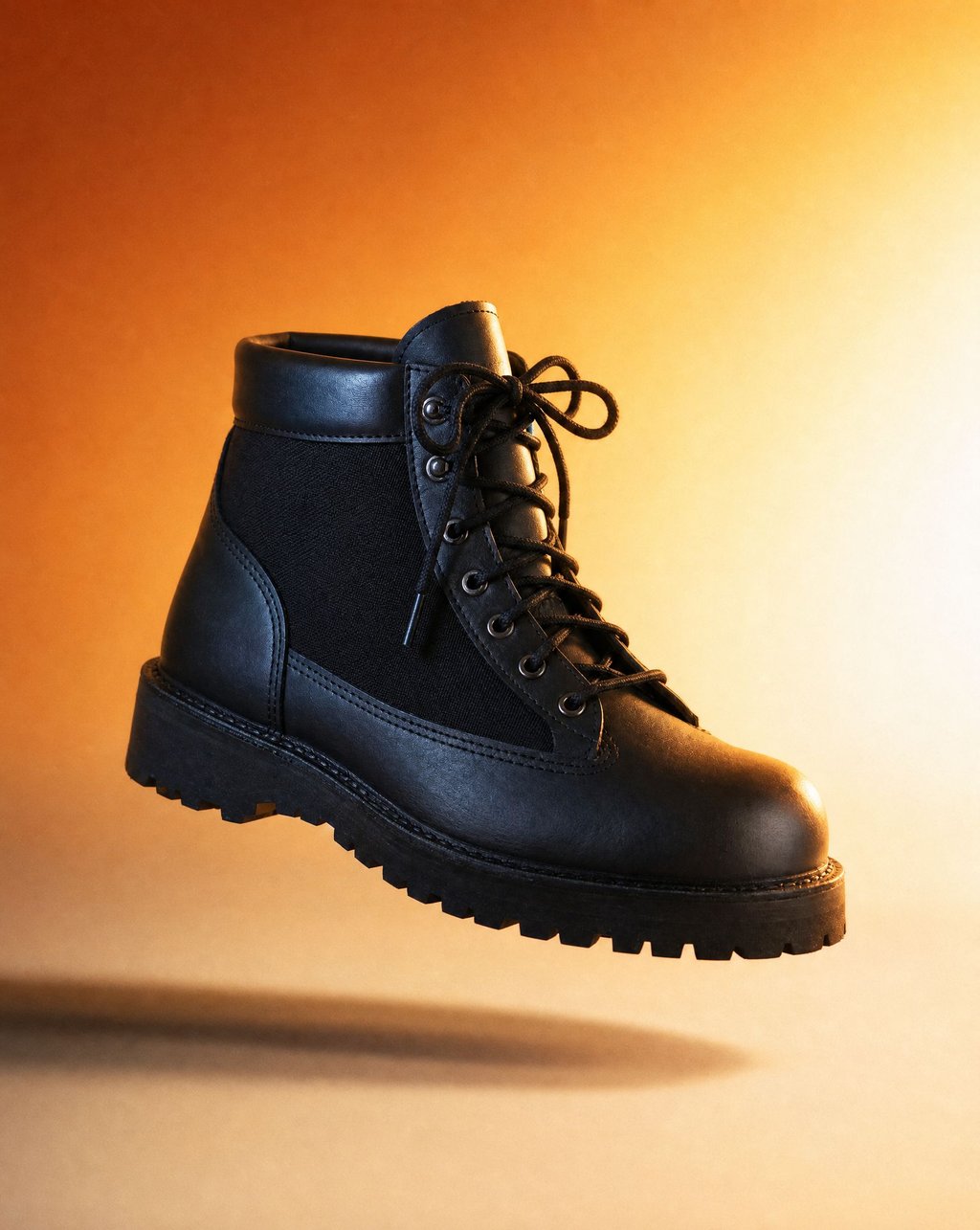 Black leather hiking boot floating in warm golden-hour light with amber glow