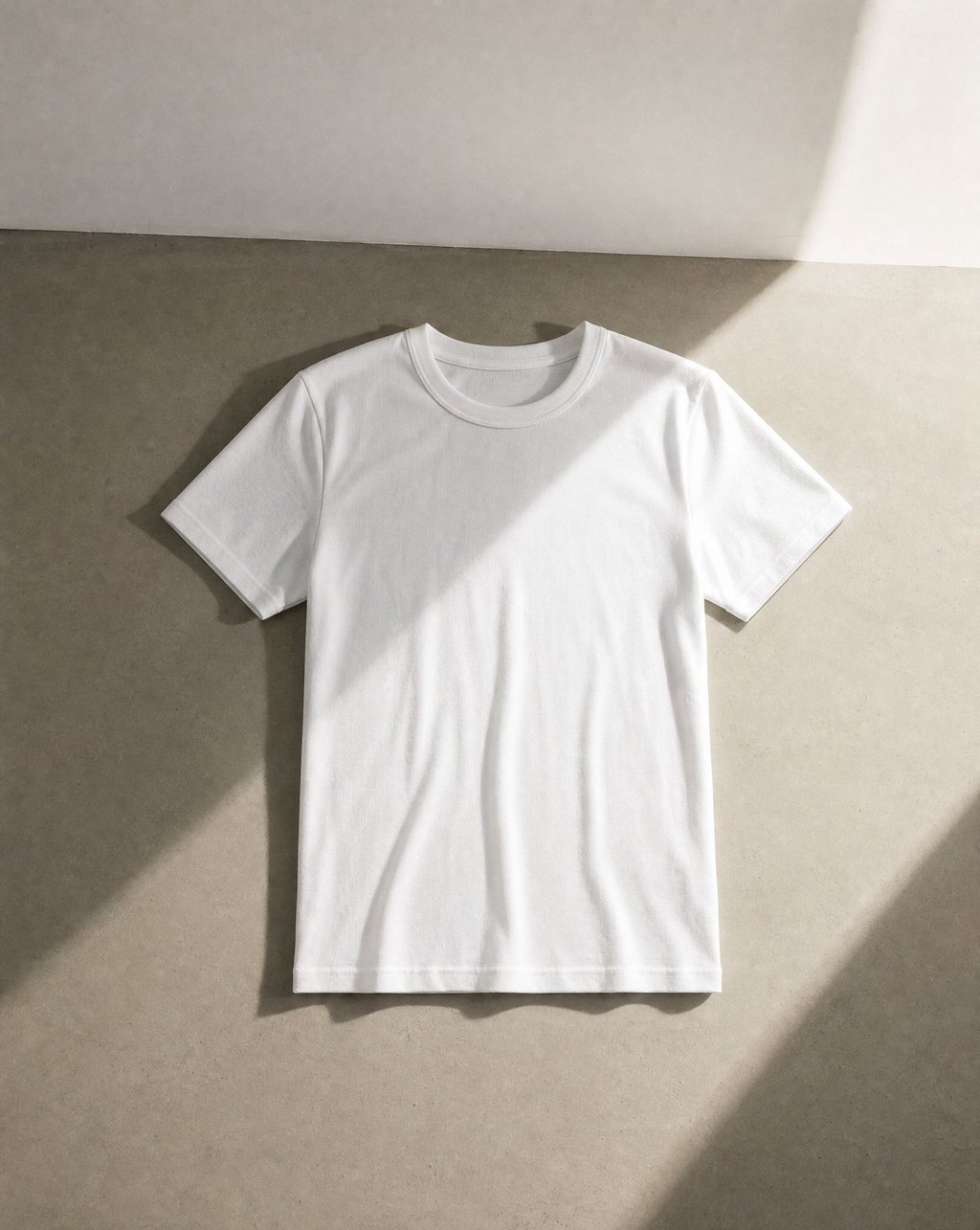 A plain white t-shirt shot flat with a strong directional shadow crossing the frame