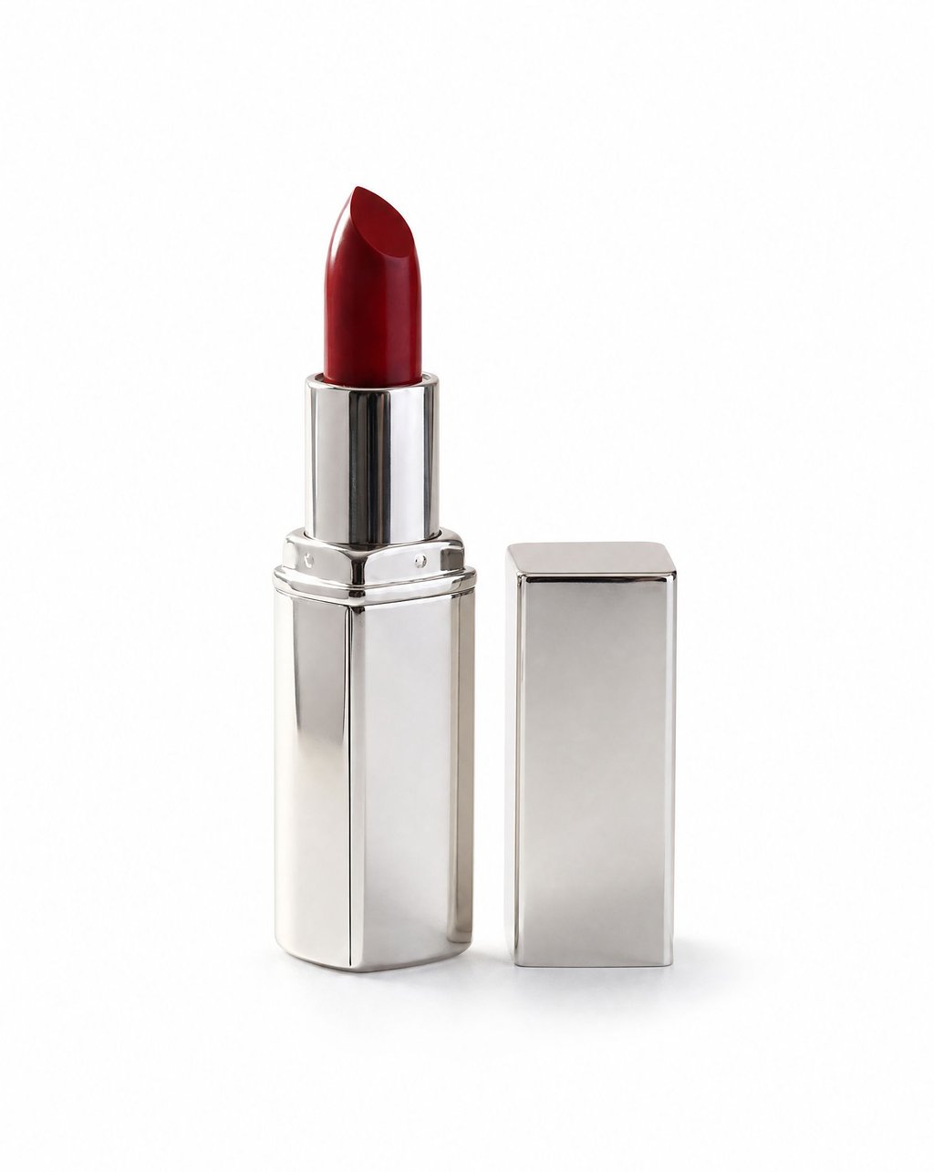 Red lipstick in a polished silver tube standing upright with its cap beside it on a white studio background