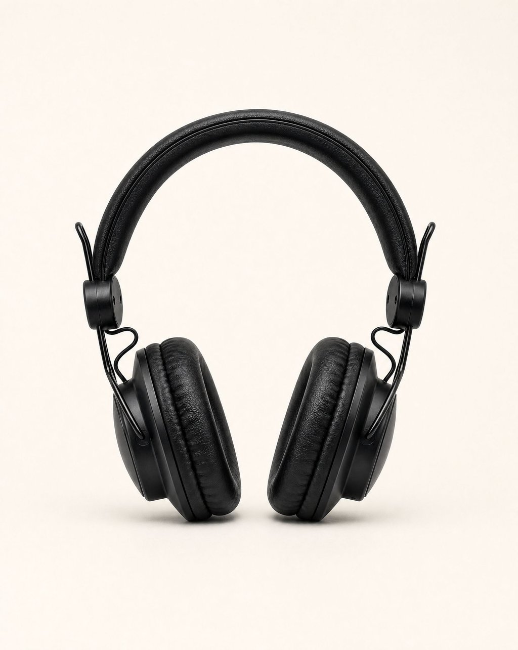 Black over-ear headphones on the same plain warm-white background under the same flat light