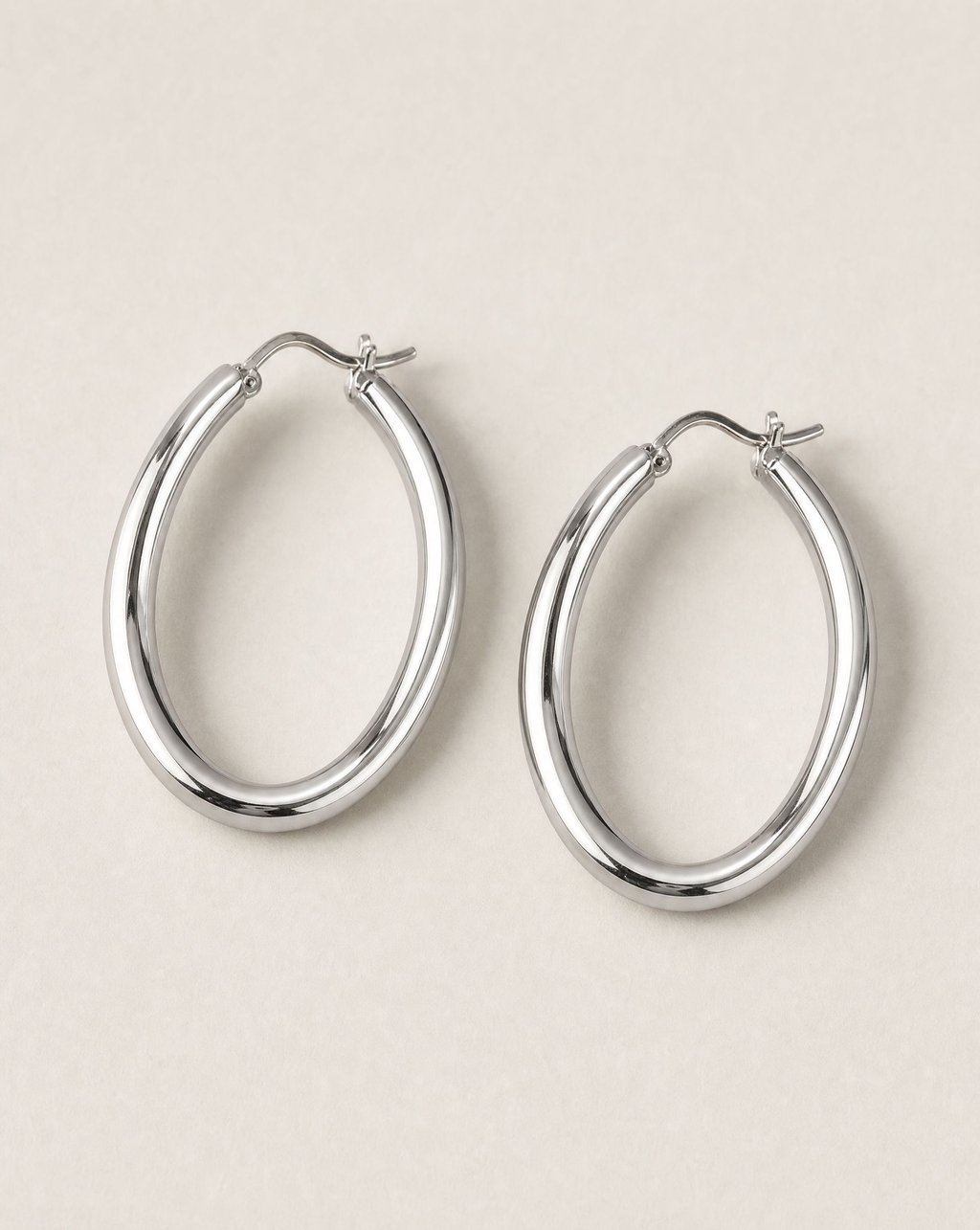 Silver hoop earrings on a pale neutral surface