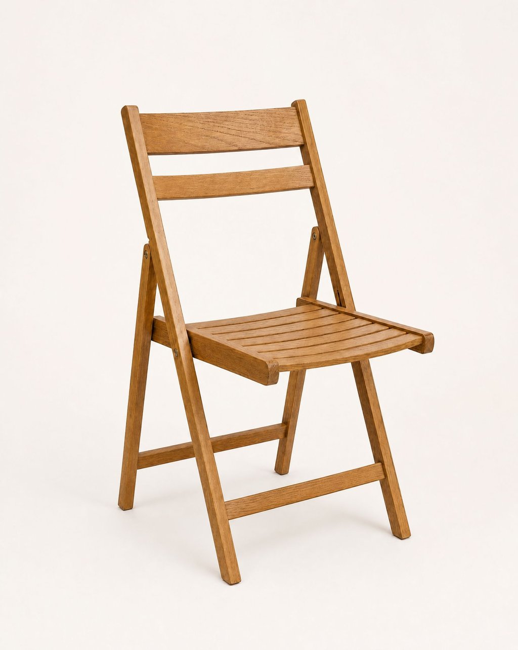 A light wooden folding chair photographed at a three-quarter angle on a plain warm-white background with a soft shadow beneath it