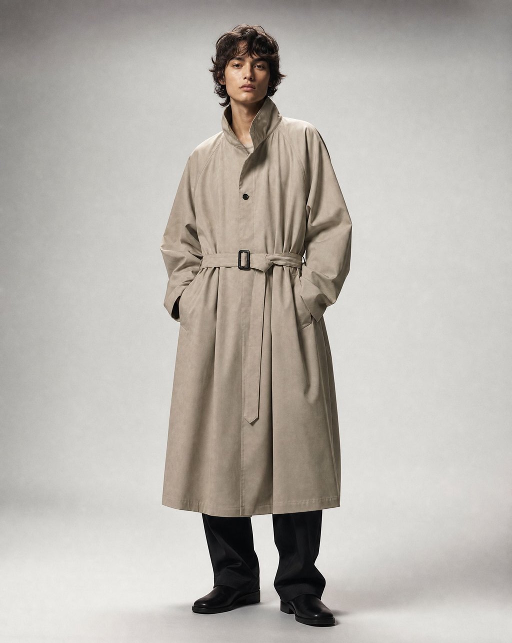 Editorial studio portrait of a model in a greige belted trench coat