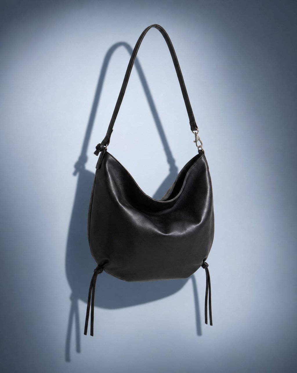 A black leather shoulder bag isolated under hard direct flash for a marketplace listing