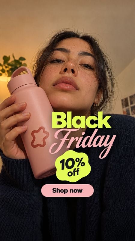 reusable water bottle sports product photo: A woman holds a pink reusable bottle close to the camera in a warmly lit interior, with bold neon-yellow and pink B…