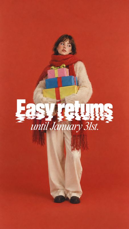 apparel look book product photo: A model in a cream outfit and red scarf holds colorful gift boxes against a vivid red studio backdrop, with bold white easy-re…
