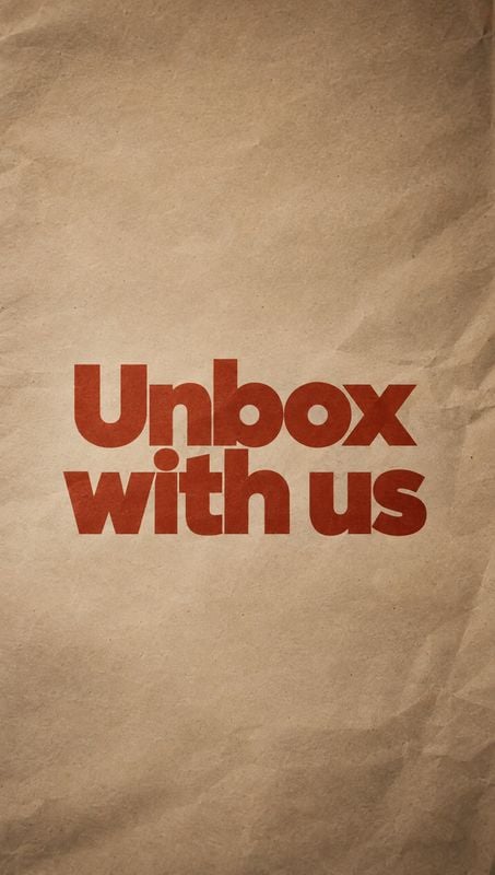 posters product photo: Bold rust-red “Unbox with us” lettering sits across the center of a textured, crumpled kraft-paper background, with warm earthy tones an…