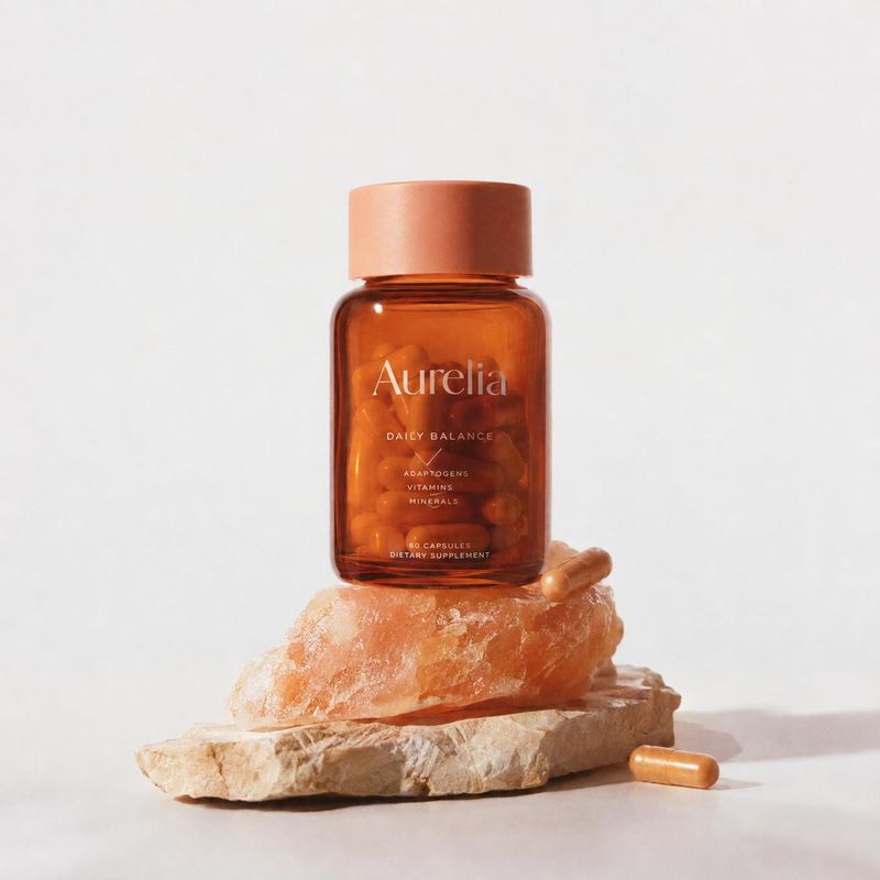 dietary supplement capsules personal care product photo: An amber bottle of dietary supplement capsules is staged on warm-toned mineral rocks with loose capsul…