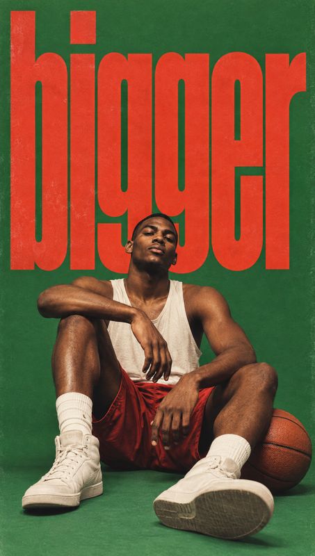 sneakers look book product photo: A seated male model in a white tank, red shorts, white socks and sneakers poses with a basketball against a textured green st…