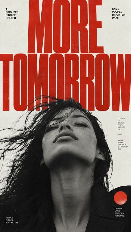 beauty close-up product photo: A dramatic black-and-white low-angle portrait of a woman with windblown hair sits beneath oversized red typography, creating a b…