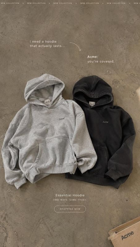 hoodies flat lay product photo: Two gray and black hoodies are arranged on a textured concrete floor, with small promotional copy and a muted neutral palette c…
