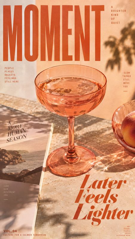pink coupe glass still life product photo: A pink coupe glass and peach sit on a sunlit stone tabletop beside a magazine, with warm shadows and oversized terra…