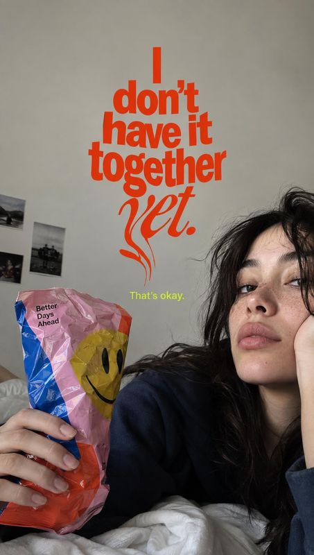 colorful packaged item with a smiley face posters product photo: A casually styled woman reclines indoors holding a colorful smiley-face package beneath bold o…