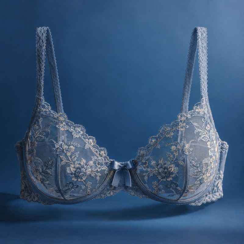 lace bra floating product product photo: A blue lace bra with delicate floral embroidery and a small satin bow is presented against a softly lit blue studio ba…
