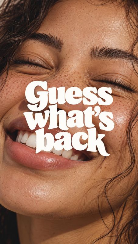 beauty close-up product photo: A tight, warmly lit close-up of a smiling woman with freckles and natural makeup, overlaid with bold white display lettering rea…