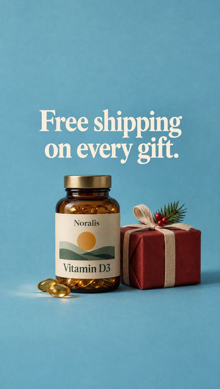 Vitamin D3 supplement bottle still life product photo: An amber bottle of Vitamin D3 supplements and a red ribbon-wrapped gift sit on a blue studio surface ben…