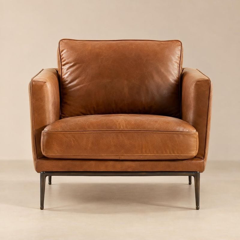 leather armchair home product photo: A cognac-brown leather armchair is centered against a warm beige studio backdrop, with soft even lighting highlighting its…