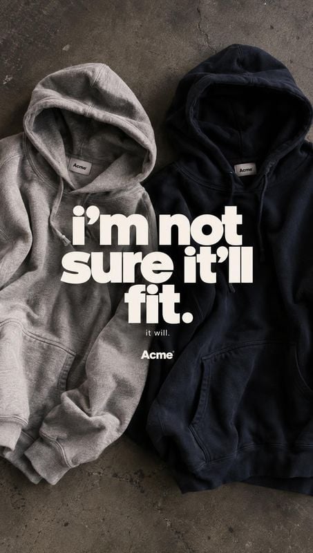 hoodies flat lay product photo: A gray and a black hoodie are arranged side by side on a textured concrete surface beneath bold cream typography, creating a mo…