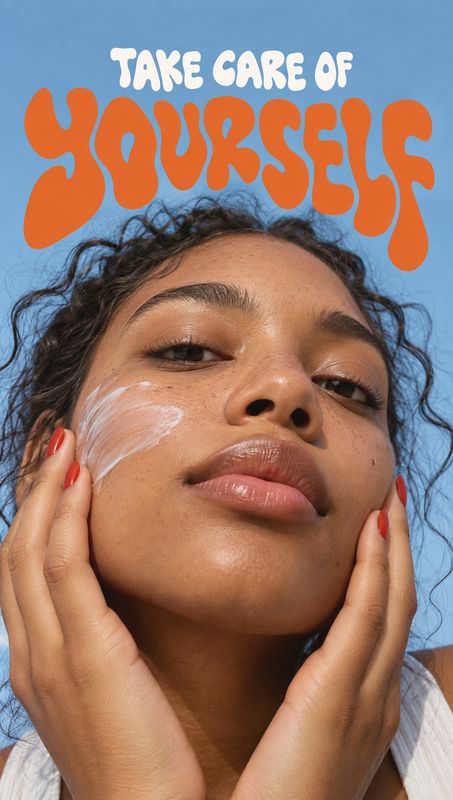 facial cream beauty close-up product photo: A close-up portrait shows a woman with cream on her cheek and hands framing her face against a clear blue backgroun…