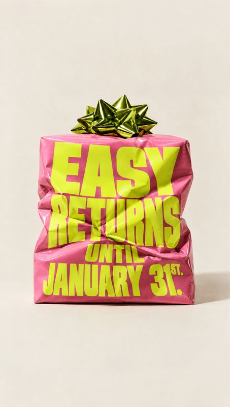packshot product photo: A crumpled pink gift-wrapped box topped with a metallic green bow displays oversized lime lettering about easy returns through January…