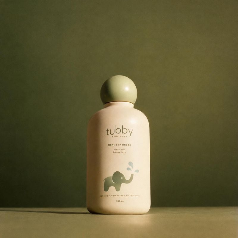 kids' shampoo beauty product photo: A softly lit kids' shampoo bottle stands centered against an olive-green studio backdrop, with generous empty space and a c…