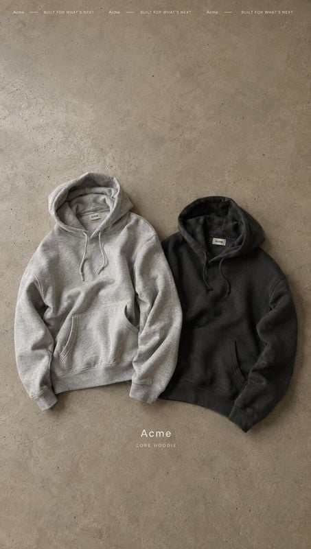 hoodies flat lay product photo: Two hoodies in light gray and black lie side by side on a textured concrete surface, lit softly from above for a muted, minimal…