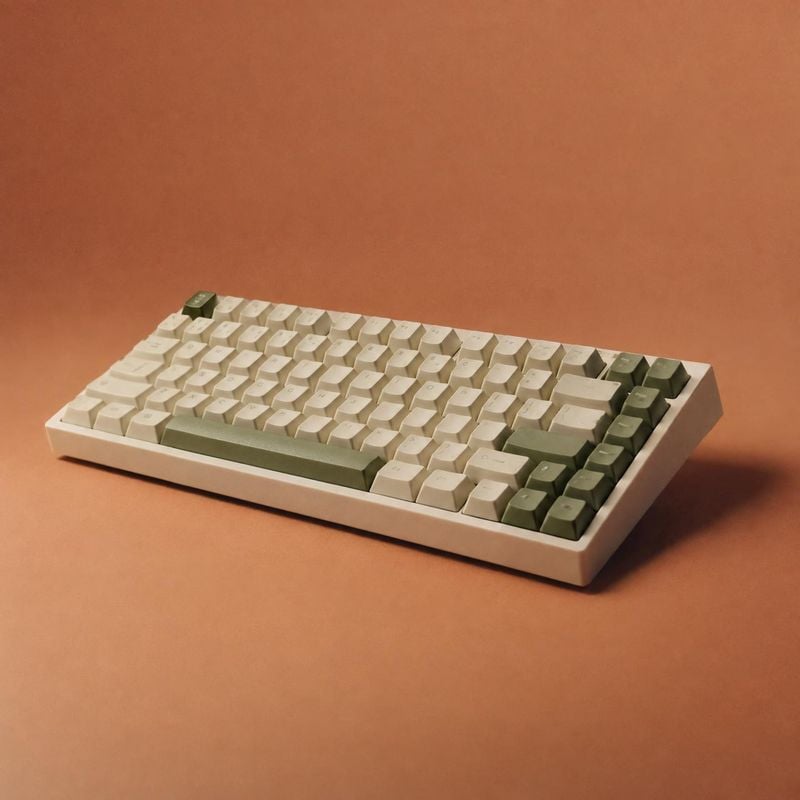 mechanical keyboard electronics product photo: A cream-and-olive mechanical keyboard is angled on a warm terracotta studio backdrop, with soft directional ligh…
