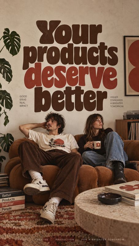 lifestyle scene product photo: Two casually dressed adults lounge on a brown sofa in a warm, plant-filled living room beneath oversized playful lettering, crea…