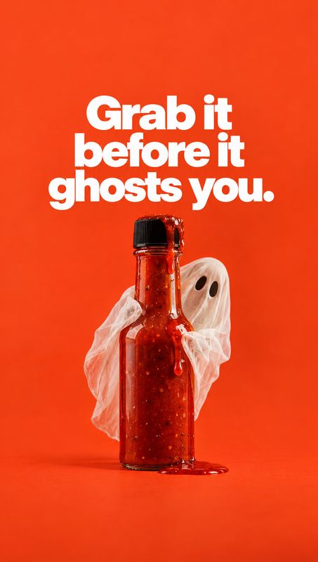 bottle of sauce halloween product photo: A bottle of red sauce drips onto a vivid orange-red studio surface while a gauzy ghost prop peeks from behind it, pair…