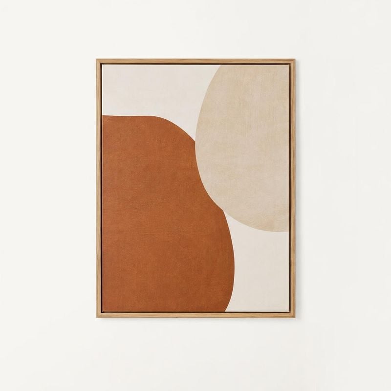 framed abstract wall art home product photo: A framed abstract print in warm rust and cream tones hangs against a pale wall, with soft even lighting and a calm…