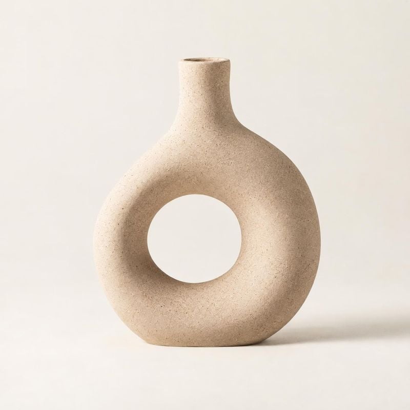 sculptural ceramic vase home product photo: A sculptural, speckled beige ceramic vase stands alone against a warm off-white studio backdrop, softly lit for a c…