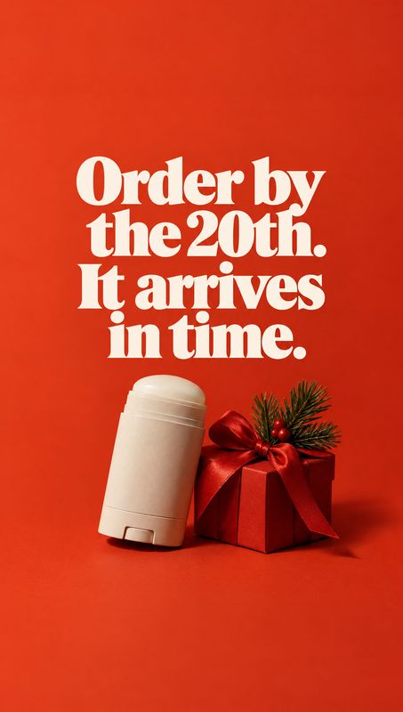 deodorant stick personal care product photo: A white deodorant stick leans beside a red gift box with a bow and evergreen sprigs against a vivid red studio bac…