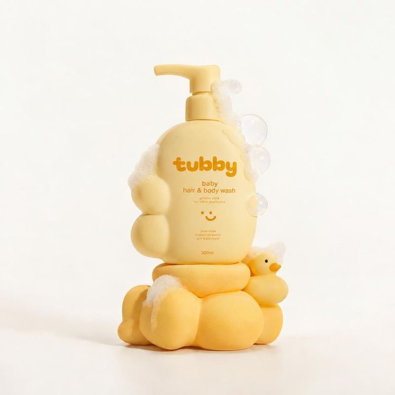 baby hair & body wash personal care product photo: A pale yellow pump bottle of baby hair and body wash sits among soft foam-like shapes and a tiny duck, lit w…