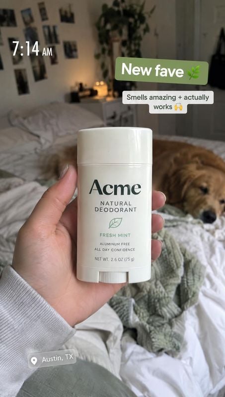 deodorant product in hand product photo: A hand presents a white Fresh Mint deodorant in a softly lit bedroom, with a sleeping dog on the bed and casual social…