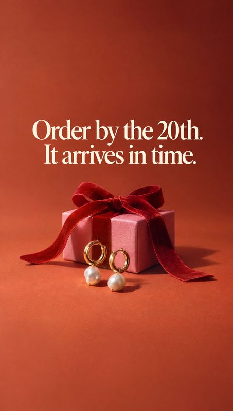 pearl drop earrings jewelry product photo: Gold hoop earrings with pearl drops rest before a pink gift box tied with a red velvet bow, beneath cream delivery-d…