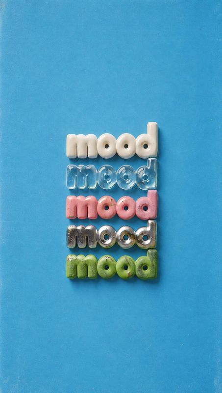 mood-shaped candy flat lay product photo: Rows of glossy, colorful candy-like letters spelling “mood” sit centered on a bright blue surface, with generous open…