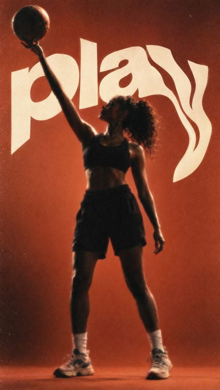 basketball action & motion product photo: A female athlete in a dark sports bra and shorts reaches overhead with a basketball against a glowing burnt-orange st…