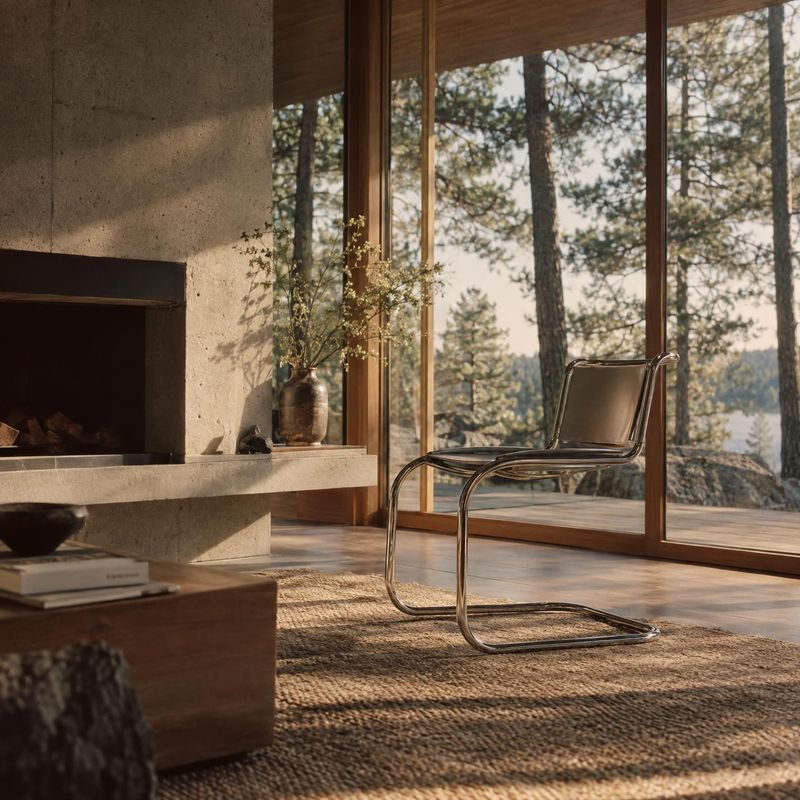 modern lounge chair room set product photo: A sculptural chrome-frame lounge chair sits on a textured rug in a warm modern living room, softly lit by late-afte…
