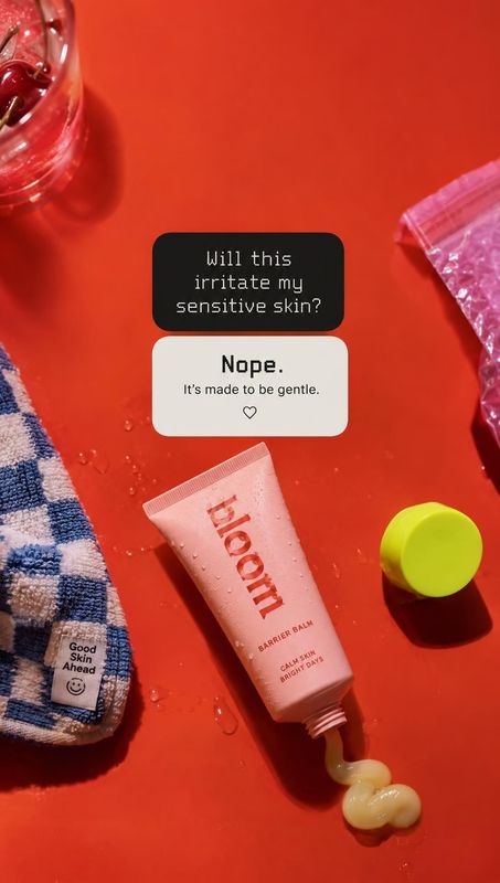 barrier balm flat lay product photo: A pink barrier balm tube and matching skincare props are arranged on a vivid red surface, with gentle shadows and conversa…