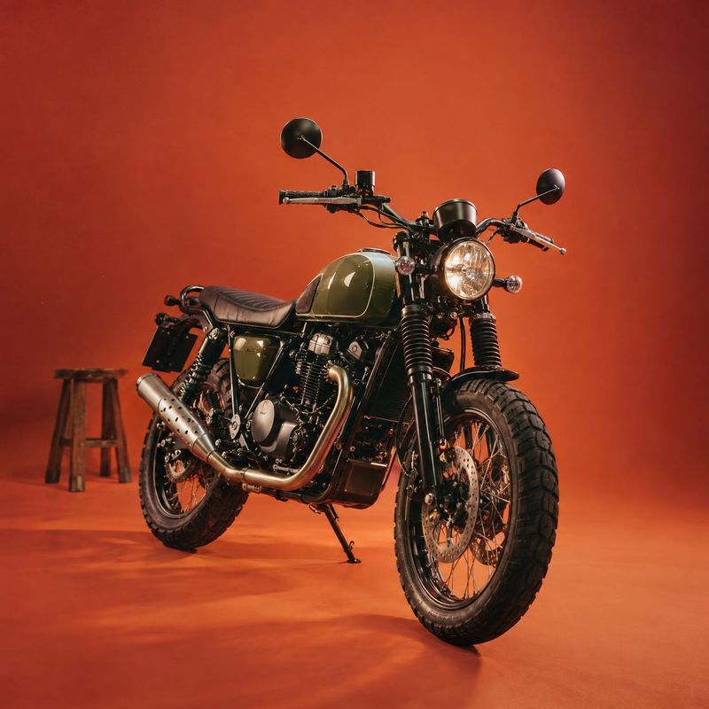 motorcycle vehicle exterior product photo: A dark olive motorcycle is staged at a three-quarter angle against a warm orange studio backdrop, with a small woode…