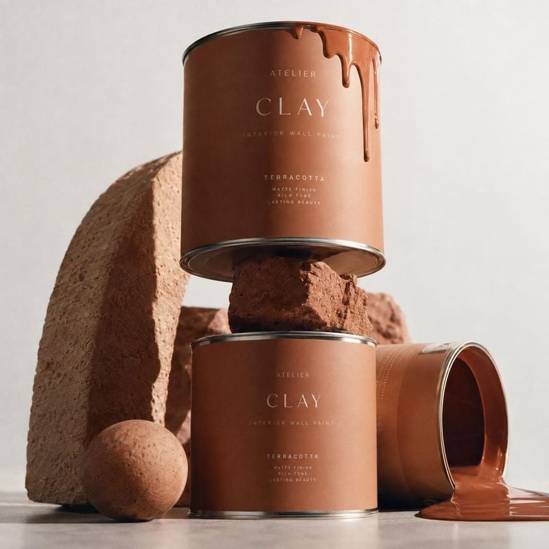 terracotta interior wall paint texture / swatch product photo: Terracotta paint tins are artfully stacked among rough clay bricks and a sphere, with paint drip…