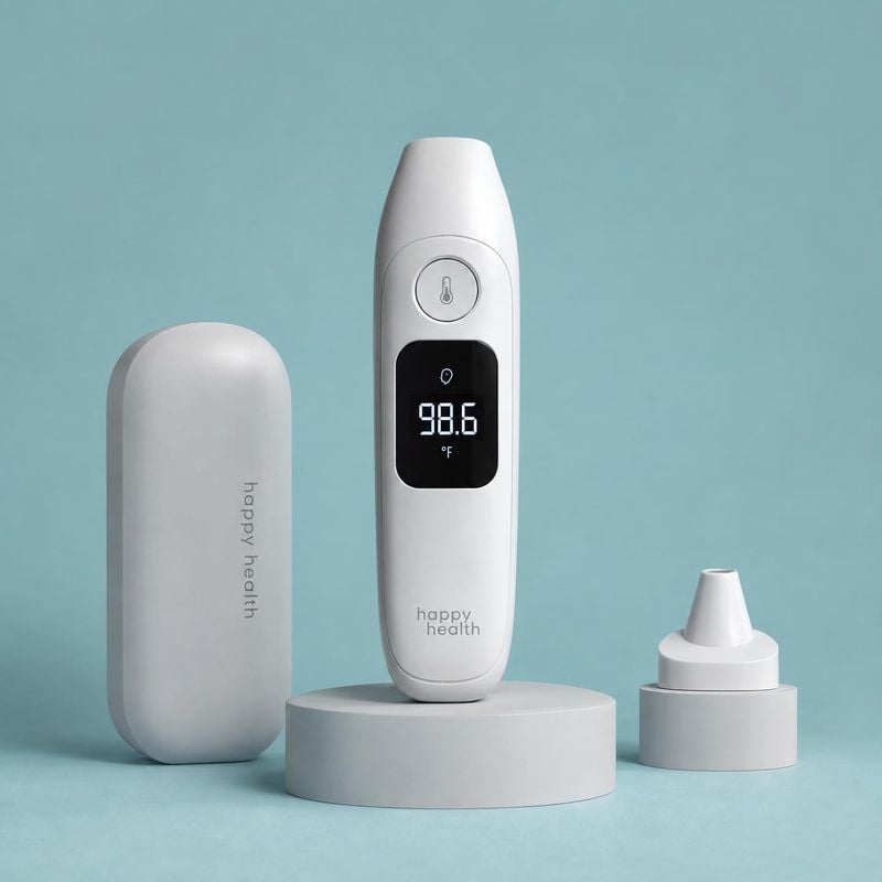 infrared thermometer personal care product photo: A white digital thermometer and matching case and attachment are arranged on pale pedestals against a soft aq…