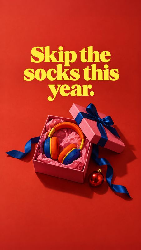headphones electronics product photo: Colorful over-ear headphones sit in an open pink gift box with blue ribbon and a red ornament on a vivid red studio backd…
