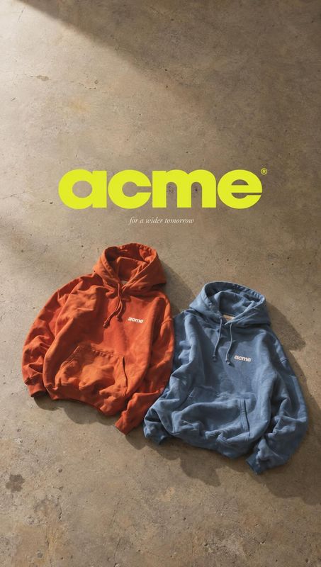 hoodies flat lay product photo: Two rust-orange and slate-blue hoodies lie on a sunlit concrete floor beneath oversized lime typography, creating a bold, casua…