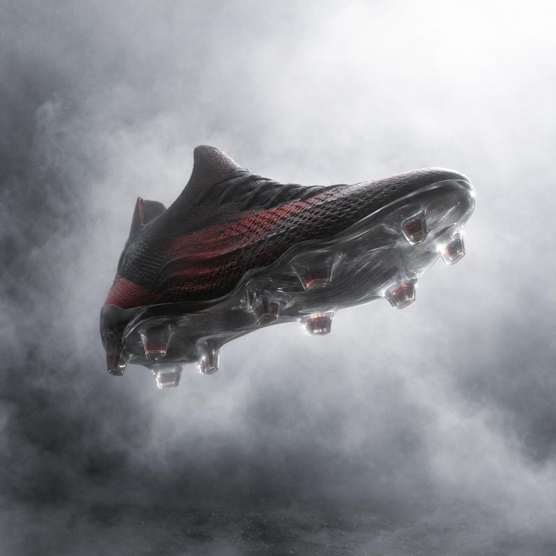 football cleat floating product product photo: A black and burgundy football cleat floats against swirling gray smoke, lit dramatically to emphasize its textur…