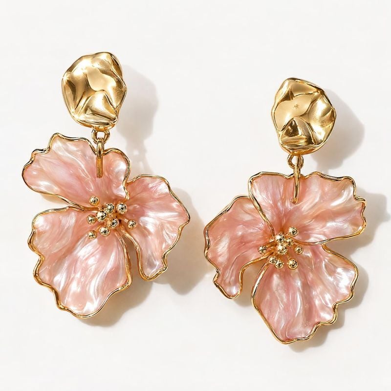 flower earrings jewelry product photo: A pair of sculptural gold-tone earrings with pink flower-shaped drops is arranged on a bright white background, lit to e…