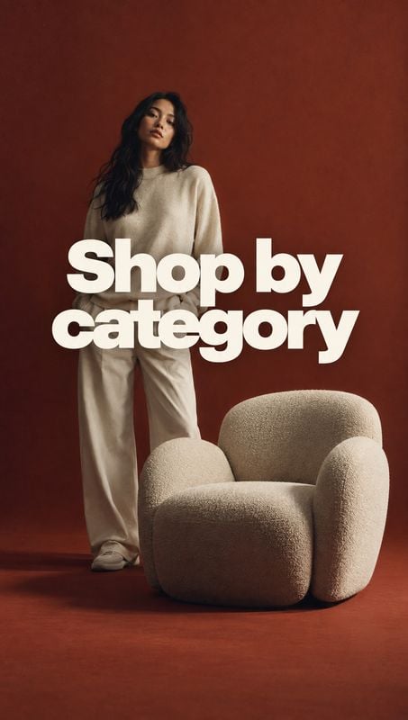 upholstered armchair black friday product photo: A model in a neutral knit outfit stands beside a textured cream armchair against a warm rust-red studio backdr…