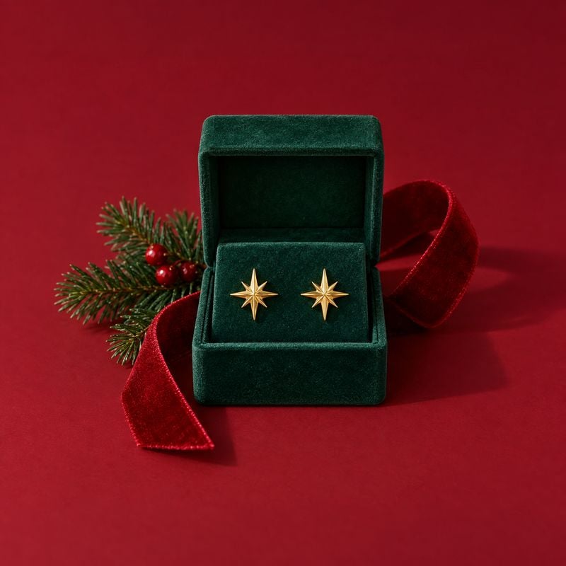 gold starburst stud earrings christmas product photo: Gold starburst stud earrings sit in an open green velvet box on a rich red surface, styled with evergreen…
